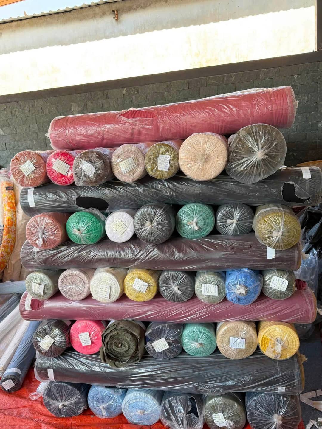 Surplus fabric rolls in many colors stacked neatly in tiers in a warehouse